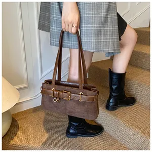 Gros plan du sac sous l'aisselle en daim marron avec boucle vintage et détails en bronze