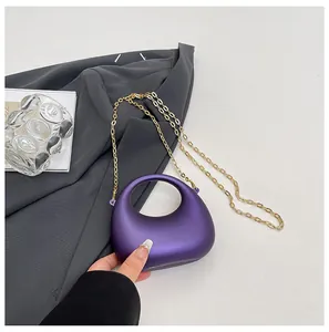 Detail van paarse halfronde acryl handtas met gouden metalen ketting en matte afwerking