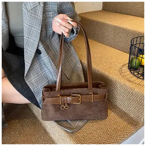 Gros plan d'un sac cabas en daim marron foncé avec boucle décorative et fermoir métallique