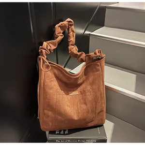 Detail of dark brown faux suede tote bag with ruched handle and minimalist front pocket
