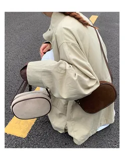 Close-up of beige and brown oval crossbody bags in textured matte leather with zip top