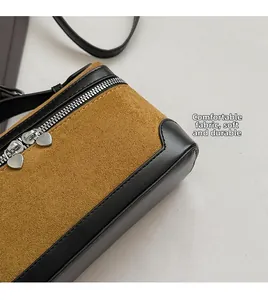Détail des fermetures éclair en forme de cœur sur un sac en daim et cuir bicolore