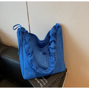 Detail view of royal blue corduroy tote bag featuring ruffle trim and drawstring closure