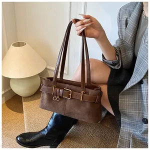 Détail d'un sac à bandoulière en daim marron foncé avec boucle métallique vintage