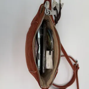 Vertikale Draufsicht auf den Innenraum der ziegelroten Crossbody-Handytasche aus Leder