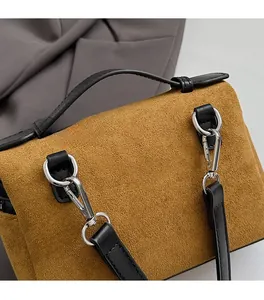 Gros plan détaillé sur les ferrures en métal poli et la texture en daim marron du sac à main