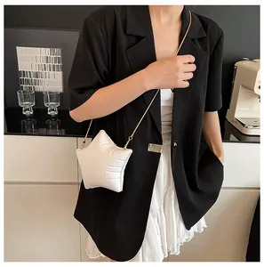 Detail of star-shaped white leather shoulder bag with gold chain on fashion model