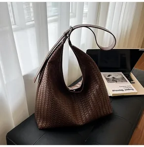 Close-up of dark brown woven leather hobo bag with adjustable strap and silver buckle