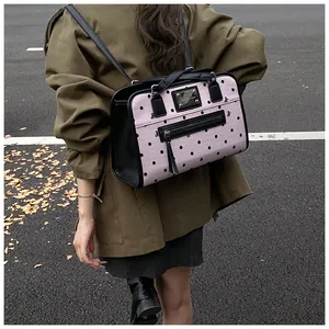 Détail d'un sac à dos rose à pois avec bretelles en cuir noir porté par un mannequin