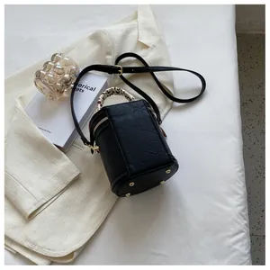 Detail of black cylindrical bucket bag with leopard scarf handle and gold studs