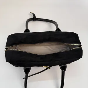 Top view of spacious interior with beige lining and gold zipper on black suede handbag