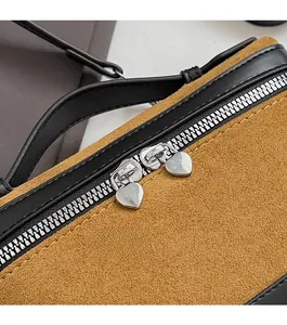 Détail du sac bicolore avec fermetures éclair argentées en cœur et doubles coutures