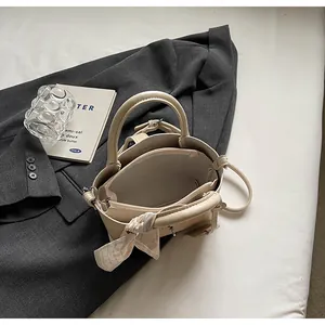 Chic cream bucket bag with floral scarf detail shown in an elegant lifestyle setting