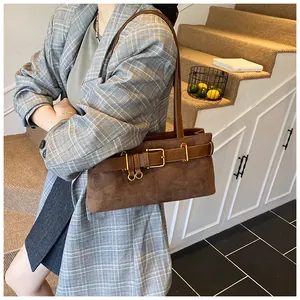 Sac à bandoulière en daim marron avec boucle de ceinture porté avec un blazer