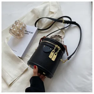 Detail of black pebbled leather bucket bag with leopard scarf and gold lock hardware