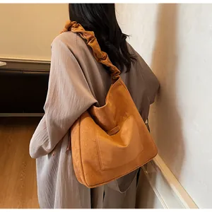 Detail of vintage brown suede hobo bag featuring a unique pleated wide shoulder strap