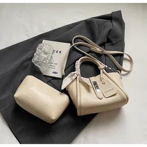 Detail of beige bucket bag set on a suit with a silk scarf handle and a small pouch
