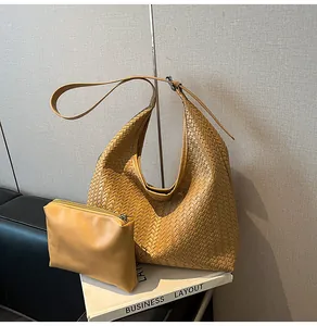 Detail of caramel woven hobo bag and matching pouch on business book prop