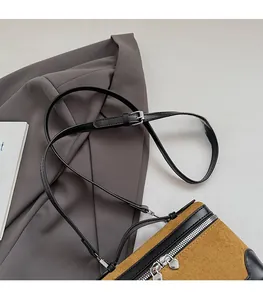 Détail du sac à main en daim marron avec double fermeture éclair et bandoulière noire