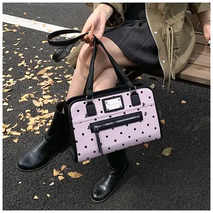 Détail du sac rose à pois avec plaque en métal argenté et nœud sur un banc en bois