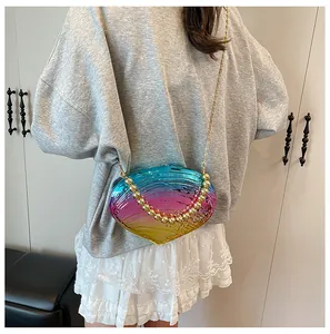 Détail de la pochette en acrylique en forme de coquillage avec dégradé arc-en-ciel et perles