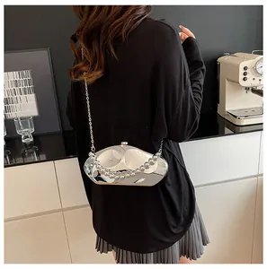 Dettaglio pochette in acrilico argento specchiato con forma fluida e manico di perle