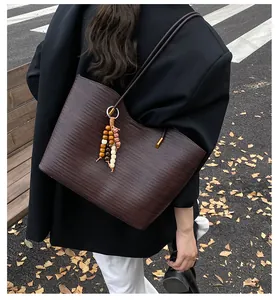 Street style shot of a dark brown woven tote bag with a decorative beaded tassel