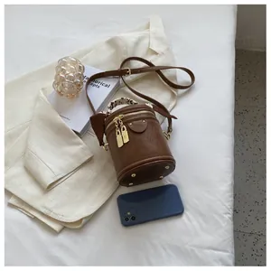 Detail of a brown cylinder bucket bag with floral silk scarf handle and gold hardware