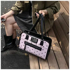 Détail du sac à pois roses avec un nœud noir décoratif et une plaque logo en métal