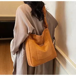 Detail view of bright orange suede shoulder bag featuring a unique scrunchie strap design