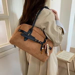 Large brown contrast tote bag with black straps and beaded charm shown from a side view