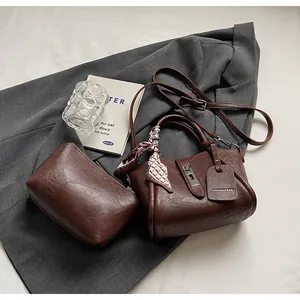 Detail of dark brown leather bucket bag set with silk scarf handle and metal clasp buckle