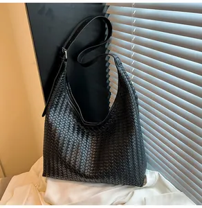 Detailed view of black woven texture and leather strap on a large shoulder tote bag