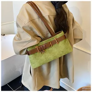 Détail d'un sac bandoulière en daim vert avec boucle de ceinture marron et anneau doré