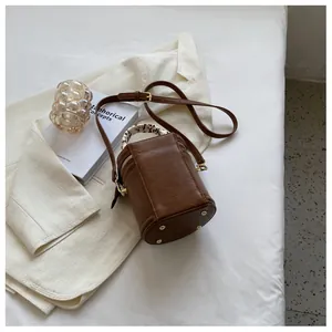 Detailed view of brown bucket bag featuring a silk scarf handle and metal feet