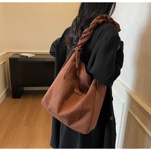 Close-up of brown suede tote bag featuring a unique ruched shoulder strap detail