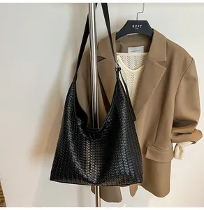 Close-up of black woven leather tote bag showing intricate texture and wide shoulder strap