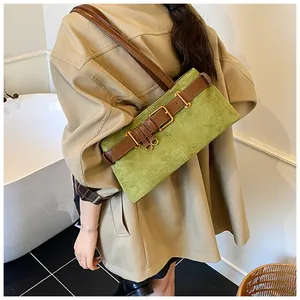 Détail du sac sous le bras en daim vert avec bandoulière en cuir brun et boucle dorée chic