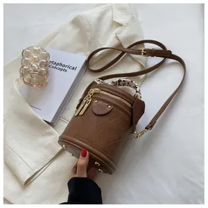 Detail of vintage brown bucket bag with silk scarf handle and golden metal feet