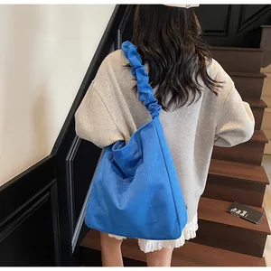 Detail of bright blue canvas tote bag featuring oversized pleated cloud-like shoulder strap