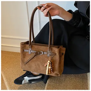 Detail der braunen Wildledertasche mit dekorativem Riemen und Anhänger aus Holzperlen