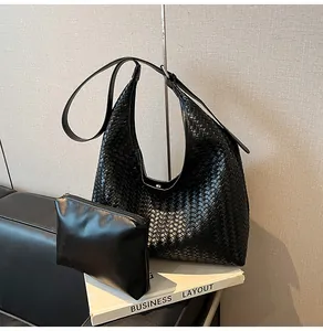 Detail of black woven hobo shoulder bag with a matching zipper pouch on white books