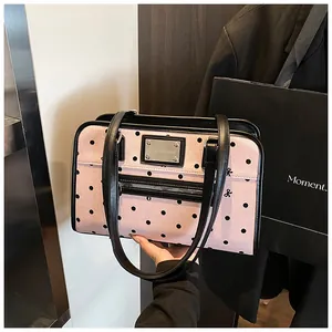 Détail d'un sac à bandoulière rose à pois avec garnitures en cuir noir et petit nœud