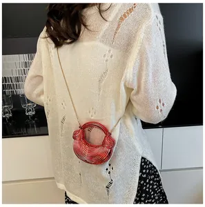 Rote metallische kreisförmige Handtasche mit Spiralstruktur und Goldkette auf Top