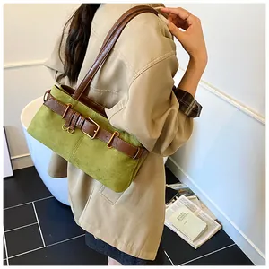 Détail du sac sous le bras en daim vert avec bandoulière en cuir marron et boucle dorée
