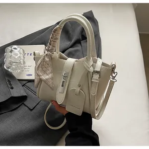 Detail of cream bucket bag with decorative silk scarf and silver twist lock on leather