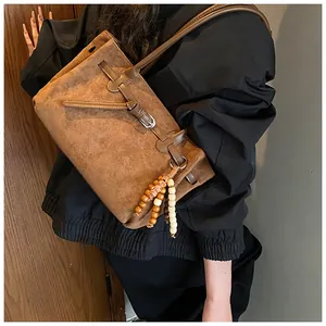 Detailaufnahme der braunen matten Ledertasche mit dekorativen Holzperlen und Schnalle