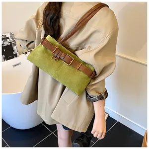 Detalle del bolso de ante verde con correa de cuero marrón y hebilla metálica retro