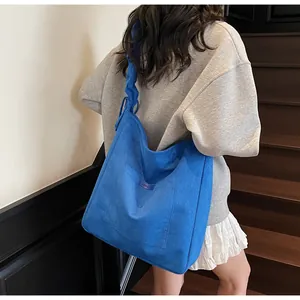 Detail of royal blue hobo bag showing large front pocket and knotted shoulder strap texture