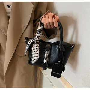 Close-up of black leather bucket bag with decorative scarf and silver hardware detail